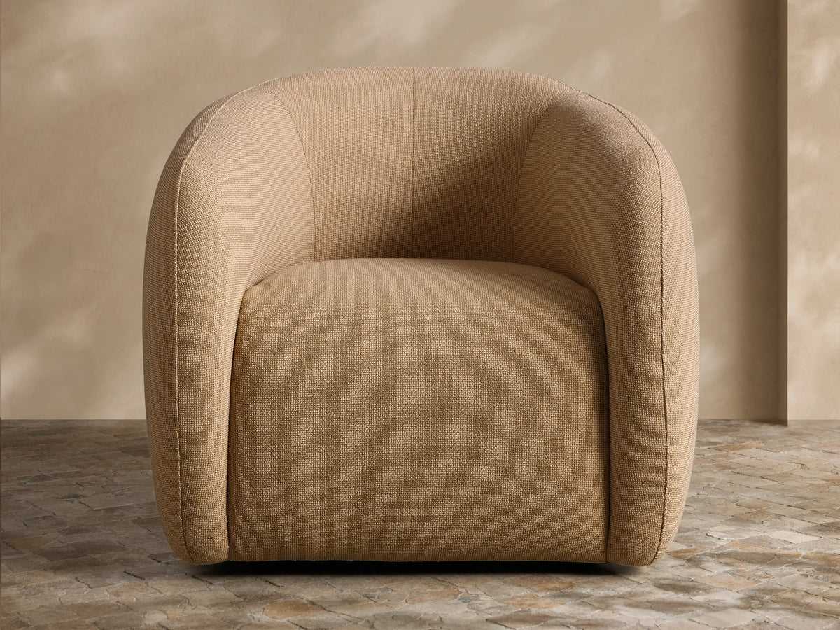Natural wicker Fresno Outdoor Swivel Chair with cream cushions on a patio, alongside a sofa and coffee table.