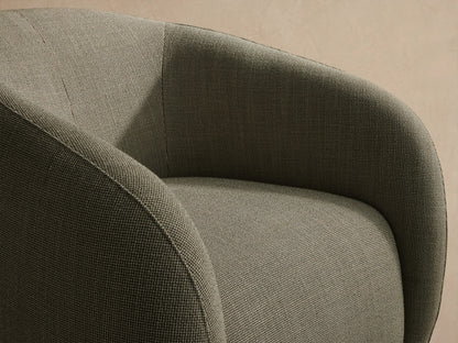 Fresno Outdoor Swivel Chair, rounded barrel-style, light greenish-grey woven upholstery, on patio tiles against a beige wall.