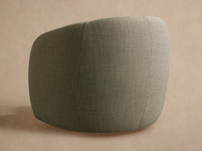 Close-up of Fresno Outdoor Swivel Chair. Dark olive-grey speckled fabric on curved back and armrest, against a light wall.