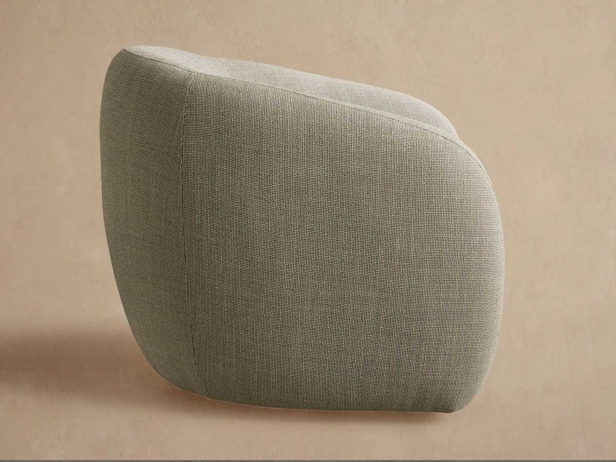 Fresno Outdoor Swivel Chair, back view. Rounded chair in speckled grey-green fabric, angled left, on a textured beige surface.