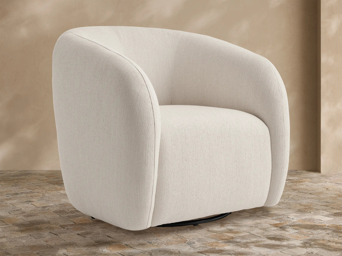 Fresno Outdoor Swivel Chair, off-white textured upholstery, rounded shape, black swivel base, on a rustic tiled floor.