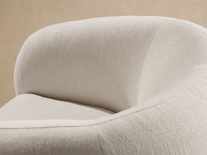 Fresno Outdoor Swivel Chair, off-white with textured fabric, a rounded shape, and a black swivel base on a stone floor.