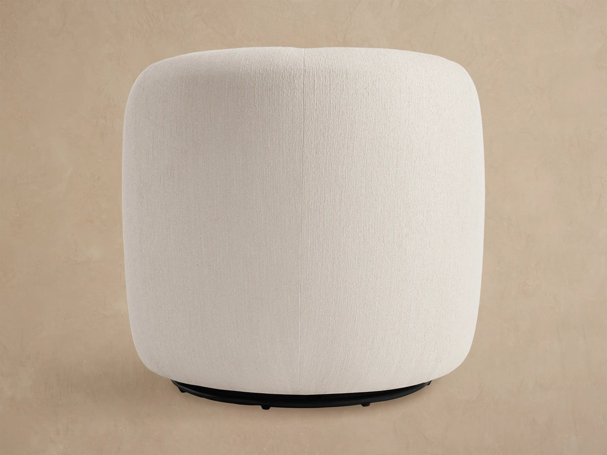 Close-up of the off-white textured upholstery on the curved back and seat of a Fresno Outdoor Swivel Chair, against a beige wall.