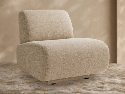 Light beige textured Gianni Outdoor Lounge Chair with rounded edges, armless, on a tiled patio floor against a warm beige wall.