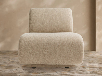 Light beige textured Gianni Outdoor Lounge Chair with rounded edges, armless, on a tiled patio floor against a warm beige wall.