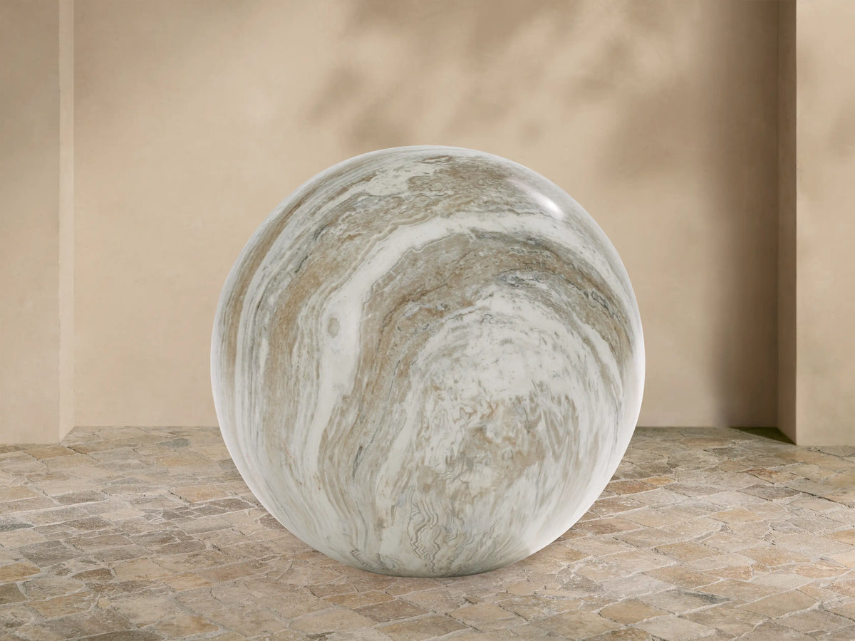 Large Garden Sphere with polished faux marble finish, white, grey & brown swirling veins, on a stone floor against a beige wall.
