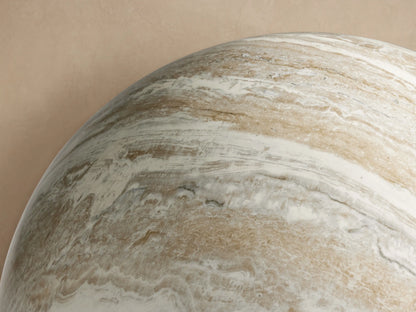 Large Garden Sphere with polished faux marble finish, white, grey & brown swirling veins, on a stone floor against a beige wall.