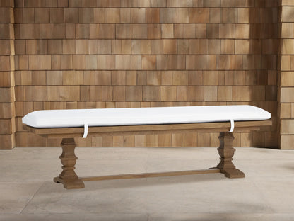 Hamptons Outdoor Dining Bench in weathered fawn teak wood with thick white cushion. Trestle style base against wood shingles.
