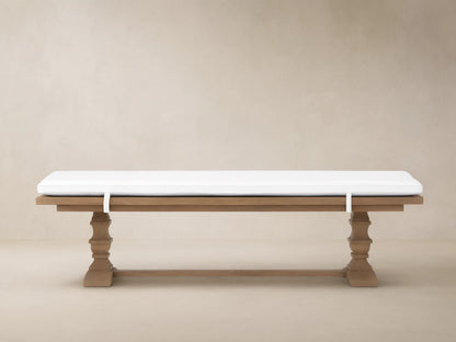 Hamptons Outdoor Dining Bench in weathered fawn teak wood with thick white cushion. Trestle style base against wood shingles.