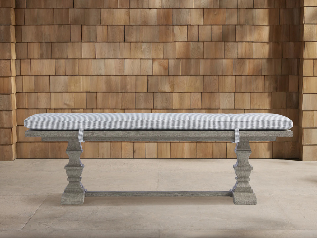Hamptons Outdoor Dining Bench in weathered fawn, with a pinstripe blue cushion, against a wood shingle wall.