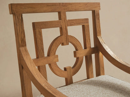 Hamptons Outdoor Dining Arm Chair, light teak wood with geometric open-patterned backrest and light beige cushion, on concrete floor.