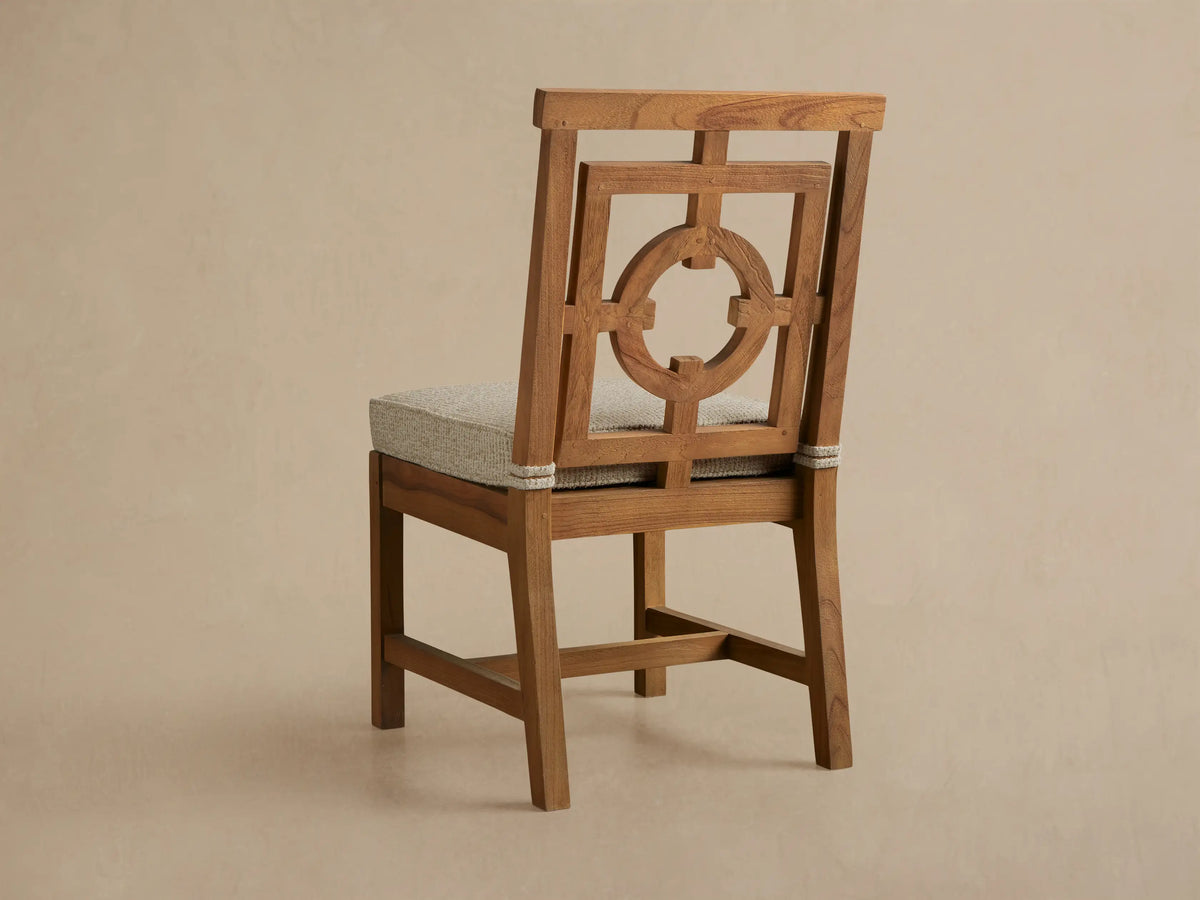 Close-up of Hamptons Outdoor Dining Side Chair, light brown teak with an intricate geometric fretwork backrest and beige seat.