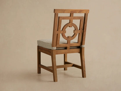 Close-up of Hamptons Outdoor Dining Side Chair, light brown teak with an intricate geometric fretwork backrest and beige seat.