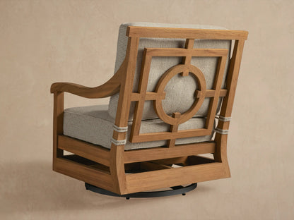 Close-up, angled view of a Hamptons Outdoor Swivel Chair with a weathered fawn teak frame, geometric back, and light gray cushions.