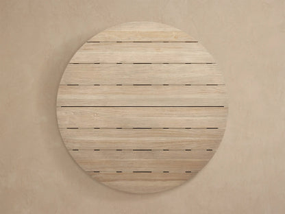 Hamptons Outdoor Round Dining Table, light weathered teak wood top with visible horizontal slats and a rounded edge, against a neutral wall.