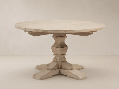 Light teak Hamptons Outdoor Round Dining Table, with carved pedestal base & splayed feet, on a patterned patio.