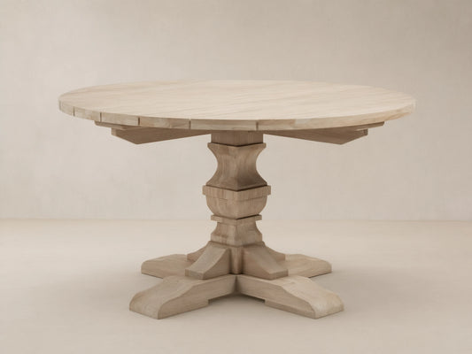Light teak Hamptons Outdoor Round Dining Table, with carved pedestal base & splayed feet, on a patterned patio.