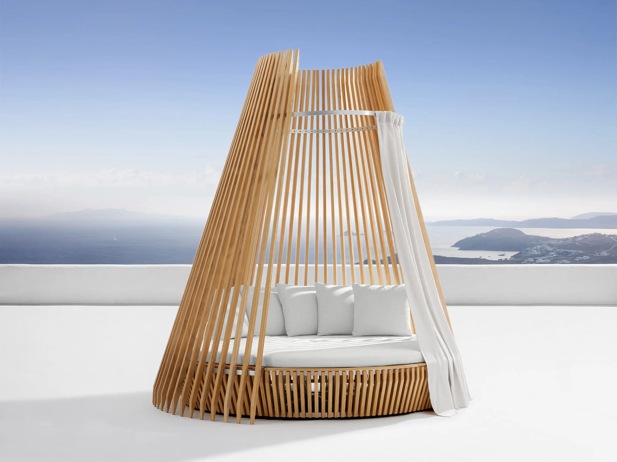 Outdoor hut with white water-repellent replacement cushions on a white patio. Blue sky and sea with islands in background.