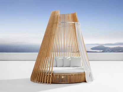Outdoor hut with white water-repellent replacement cushions on a white patio. Blue sky and sea with islands in background.