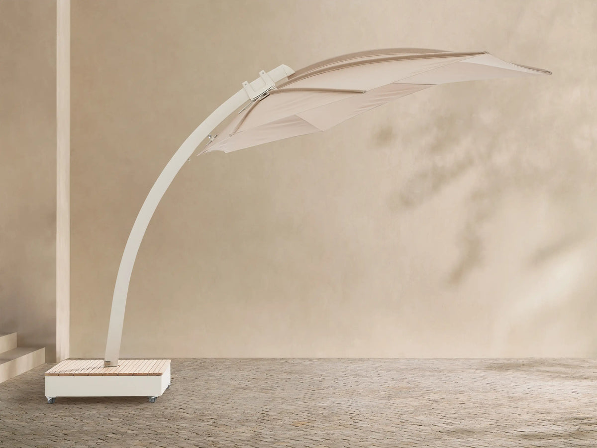 Icarus Outdoor Umbrella in Sand with an open, sand-colored canopy and curved white frame, angled over a slatted wooden wheeled base.