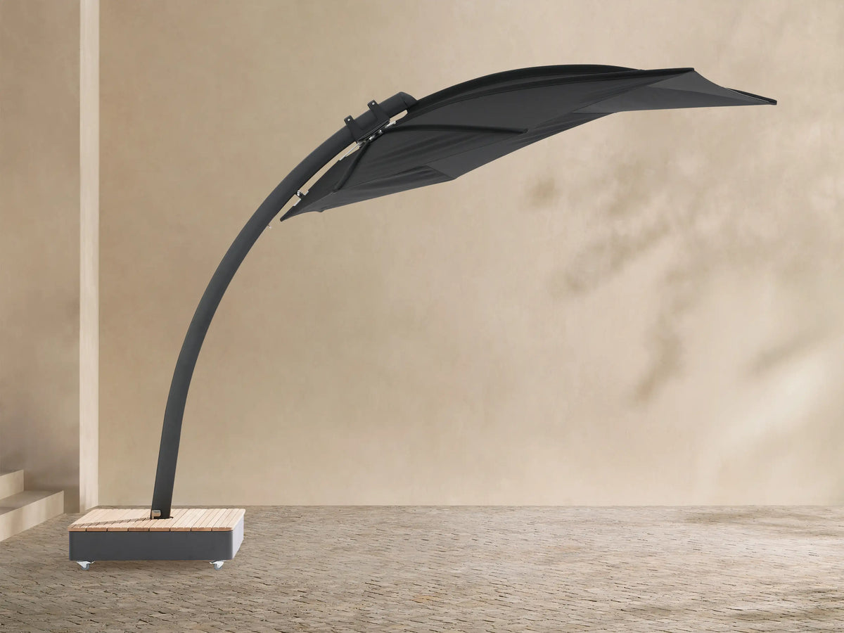 Black Icarus outdoor umbrella, open and tilted to the right, with a curved dark gray pole and a light wood-slatted base on wheels.