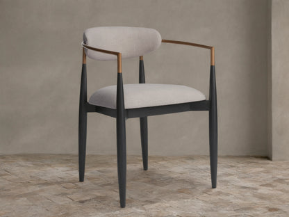 Jagger Outdoor Dining Arm Chair with black wooden frame, light grey cushions, and bronze-toned metal armrests, angled view.