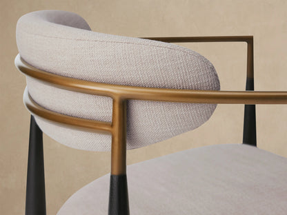 Jagger Outdoor Dining Arm Chair with light grey cushions, dark wood frame, light curved armrests, and brass accents, front view on tiled floor.