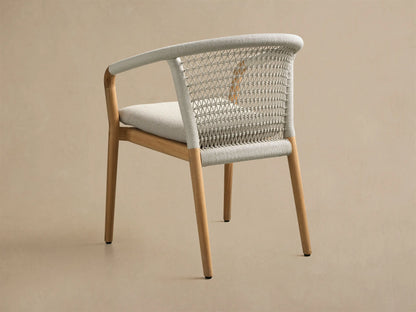 Front view of the Kaia Outdoor Dining Chair with Cushion, featuring a natural teak wood frame, light gray woven back, and light gray cushion.