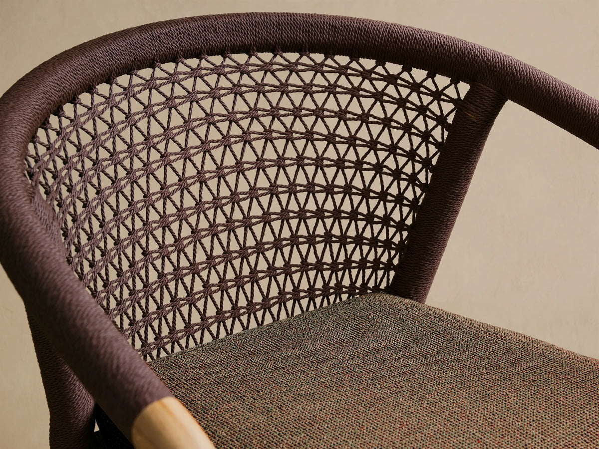 Front view of the Kaia Outdoor Dining Chair with Cushion, featuring a natural teak wood frame, brown woven back, and seat cushion.