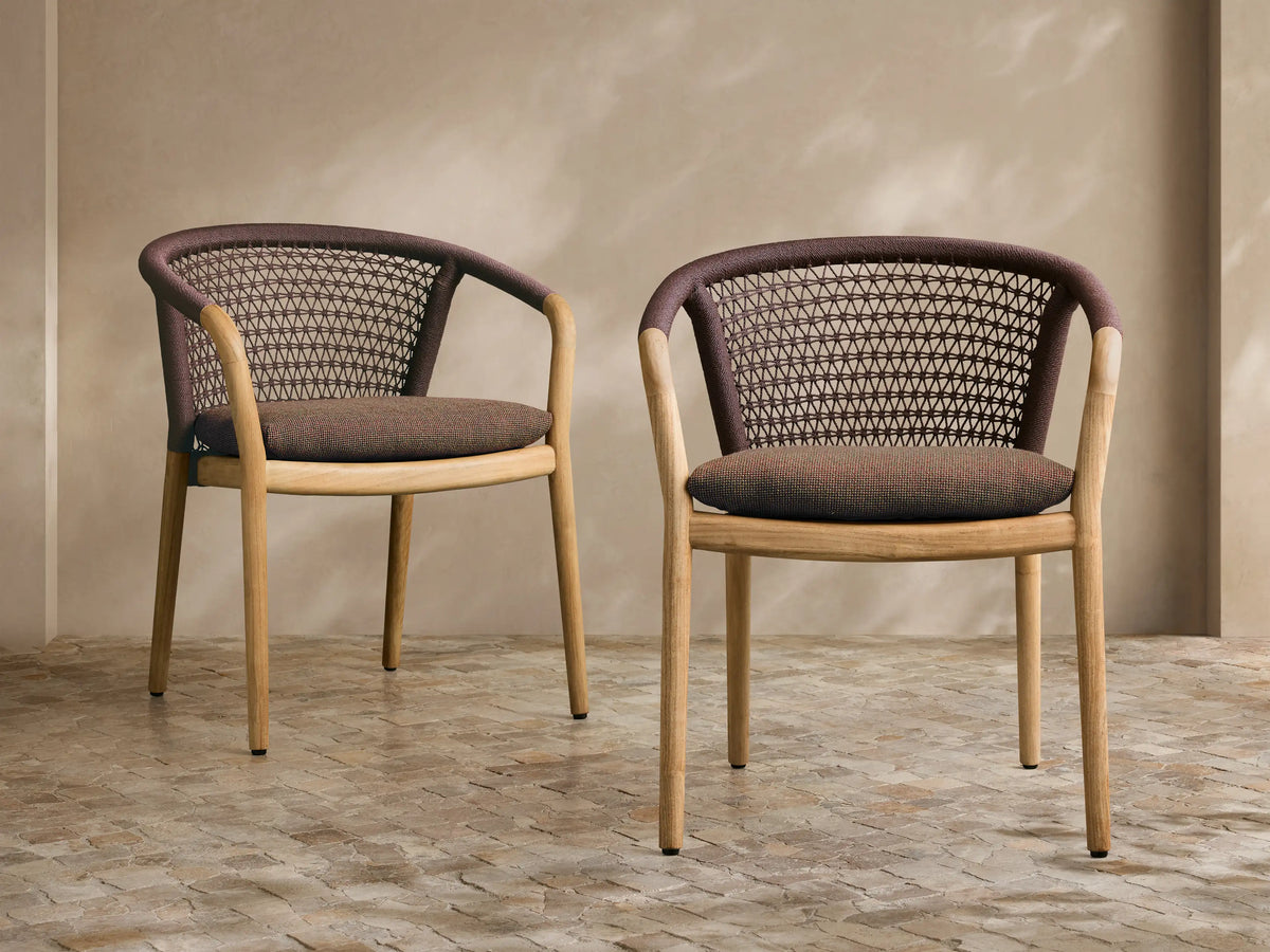 Angled rear view of the Kaia Outdoor Dining Chair with Cushion, featuring a natural teak frame, dark brown woven back, and speckled grey cushion.
