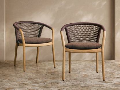 Angled rear view of the Kaia Outdoor Dining Chair with Cushion, featuring a natural teak frame, dark brown woven back, and speckled grey cushion.