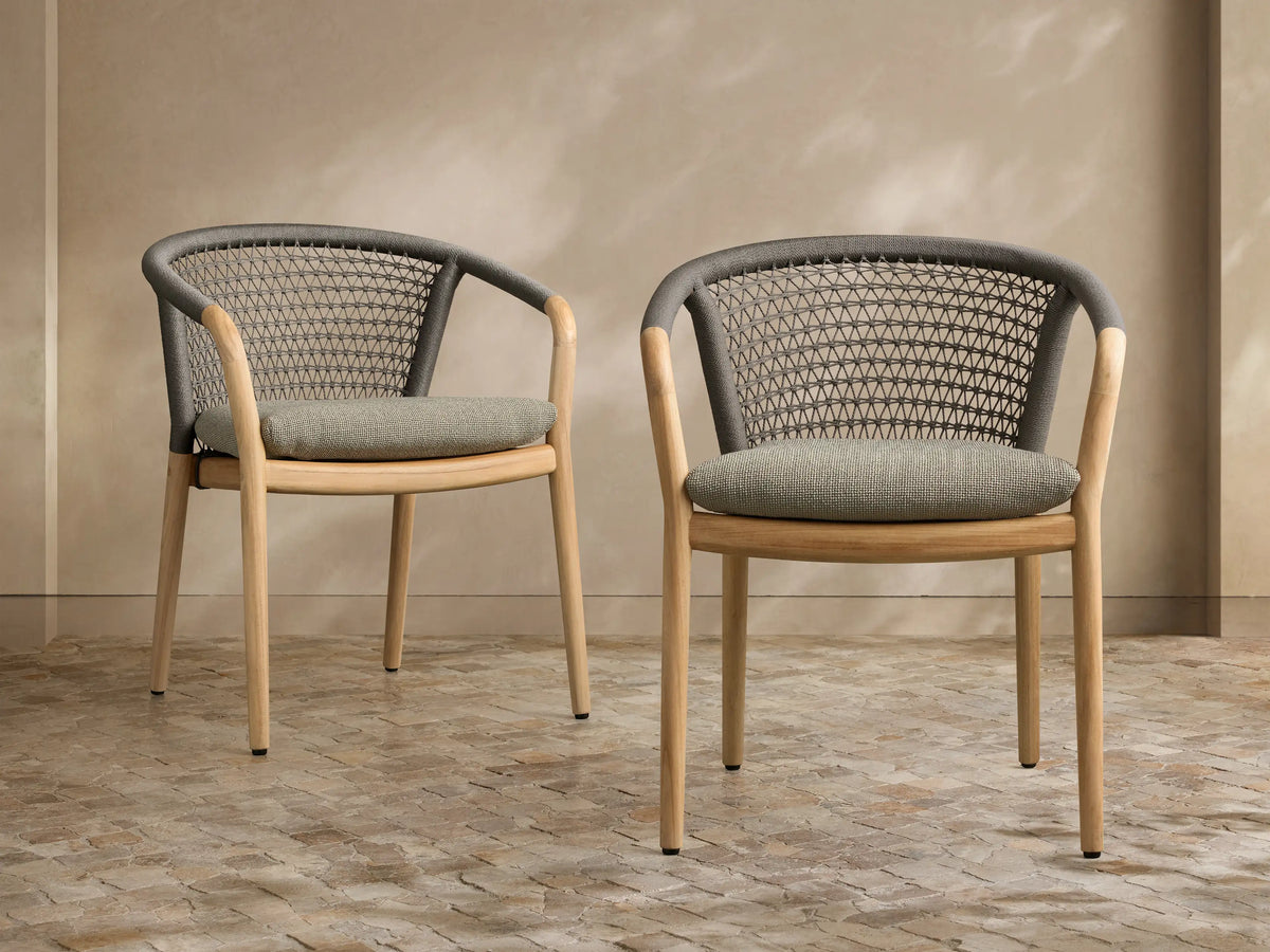 Front view of two Kaia Outdoor Dining Chair with Cushion, featuring natural teak frames, dark grey woven backs, and sage green cushions.