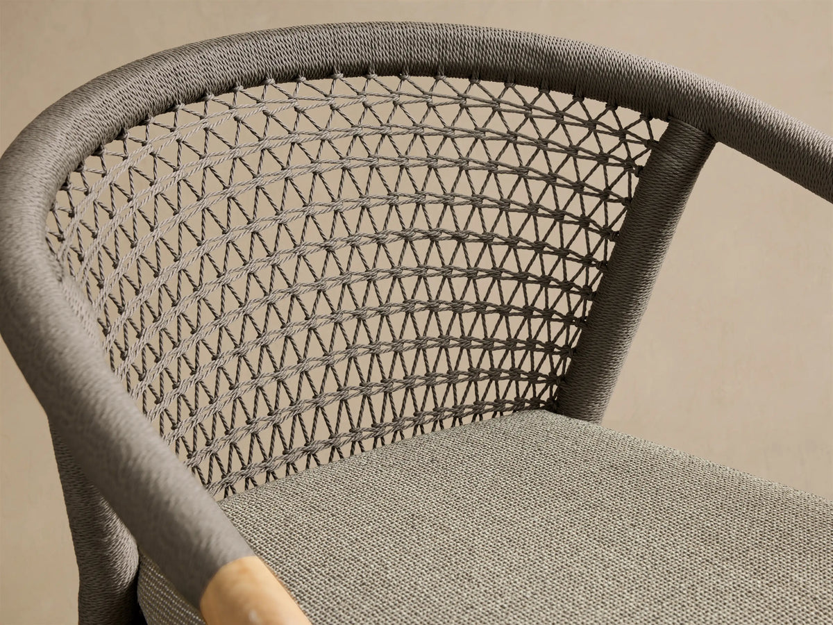 Front view of the Kaia Outdoor Dining Chair with Cushion, featuring a natural teak frame, a grey woven backrest, and a matching grey cushion.
