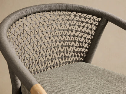 Front view of the Kaia Outdoor Dining Chair with Cushion, featuring a natural teak frame, a grey woven backrest, and a matching grey cushion.