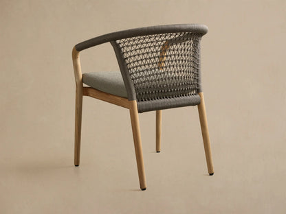 Close-up view of the gray Kaia Outdoor Dining Chair with Cushion, featuring an intricately handwoven rope backrest and a light gray fabric cushion.