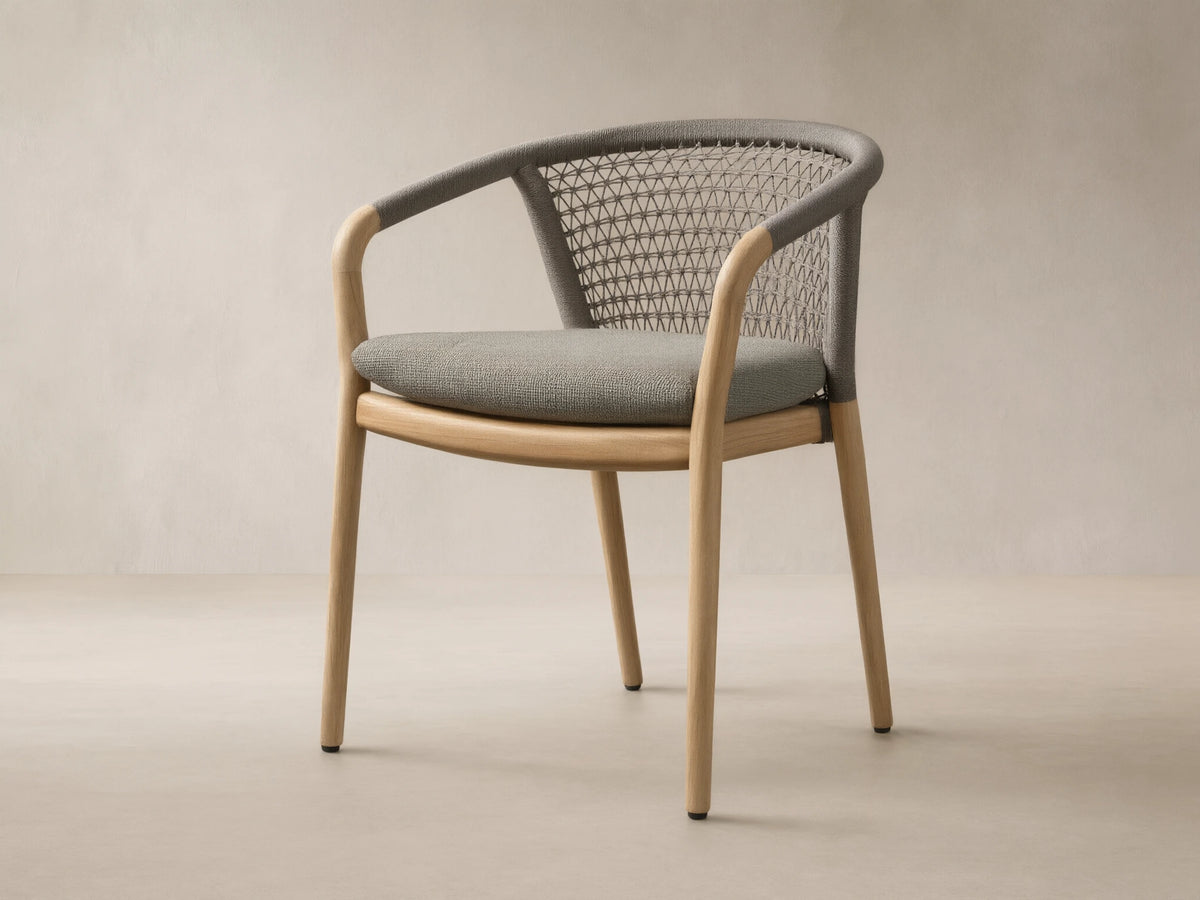 Front view of the Kaia Outdoor Dining Chair with Cushion, featuring a natural teak wood frame, grey woven back, and light grey cushion.
