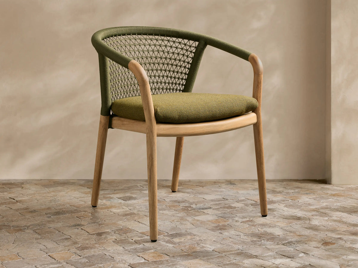 Stacked view of two natural teak Kaia Outdoor Dining Chairs with Cushion, featuring dark green woven rope backs.