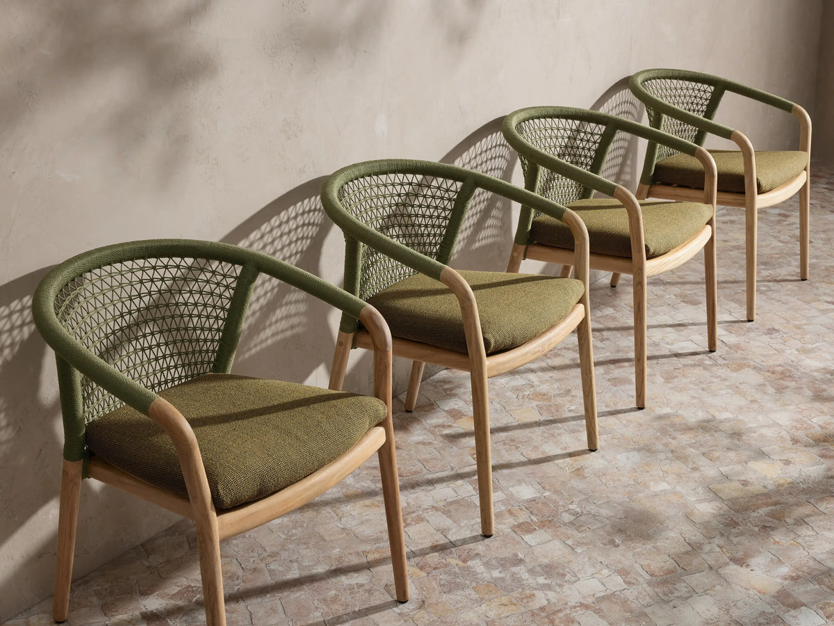Four green Kaia Outdoor Dining Chairs with Cushion, with green woven rope backs, green cushions, and natural teak frames, in a row.