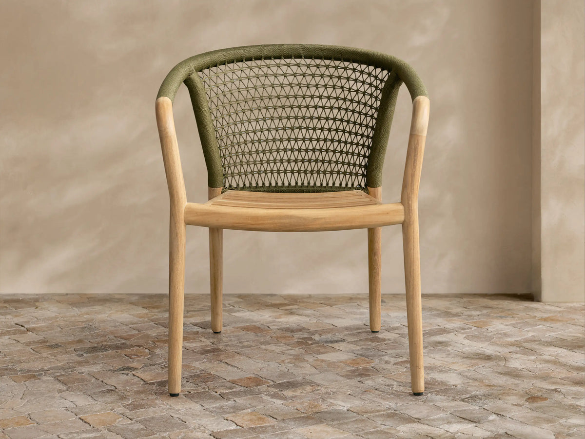 Stacked Kaia Outdoor Dining Chair with Cushion, featuring natural teak frames and dark green woven backs.