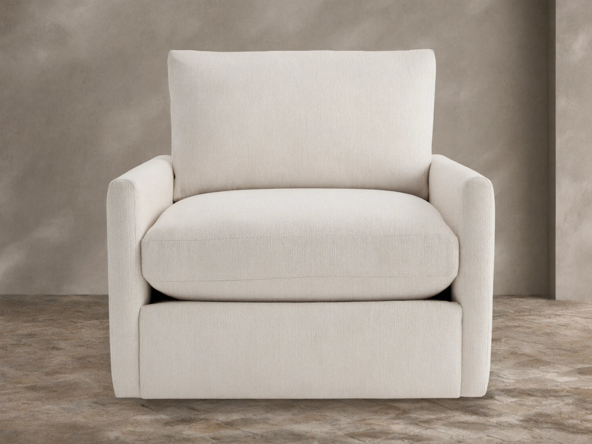 Kipton Outdoor Swivel Chair in cream fabric, front-facing, with plush seat/back cushions, on stone patio.