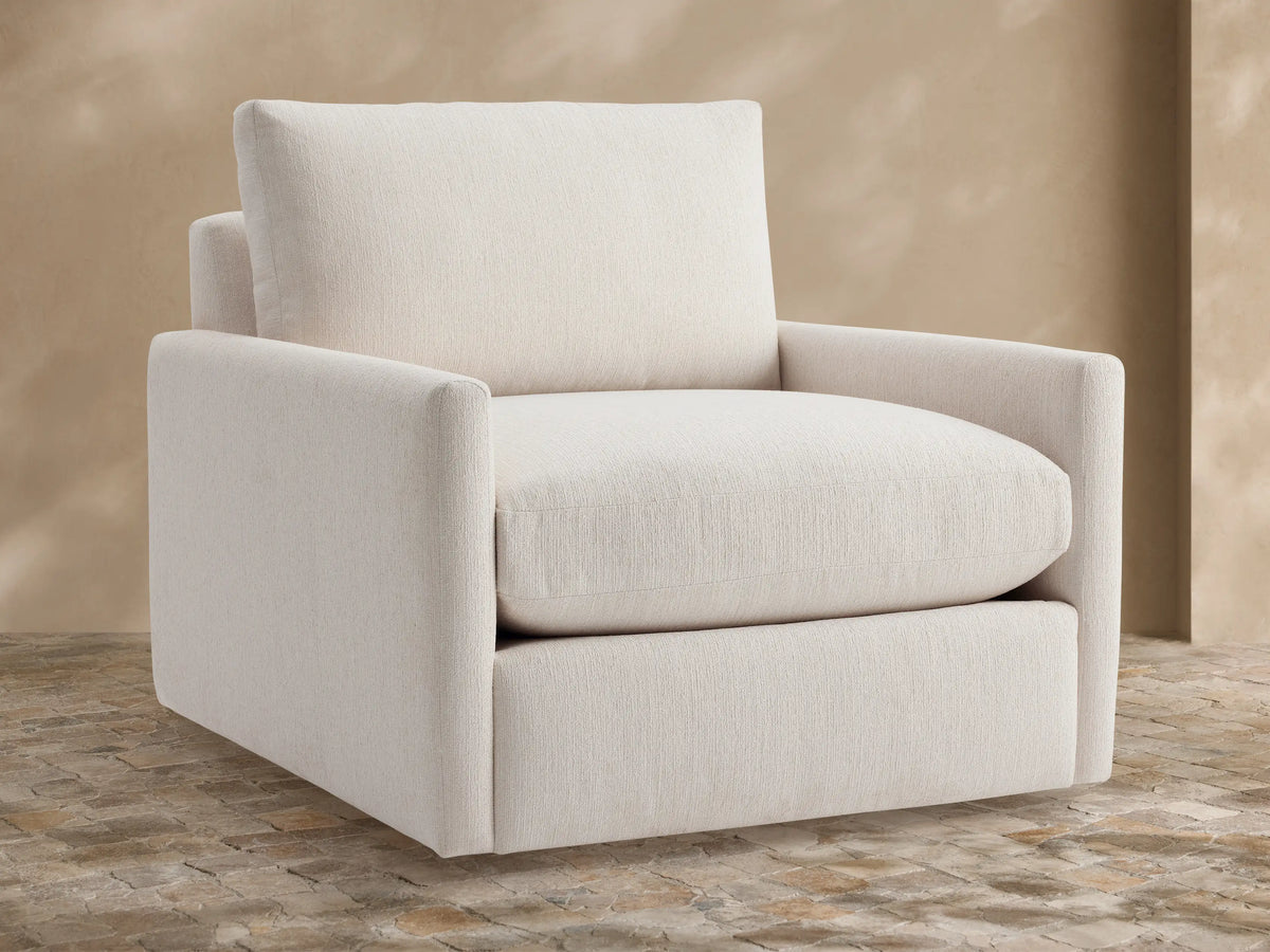Kipton Outdoor Swivel Chair in cream fabric, front-facing, with plush seat/back cushions, on stone patio.