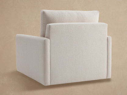 Close-up of a Kipton Outdoor Swivel Chair, showing its off-white textured back cushion, armrest, and seat against a beige wall.