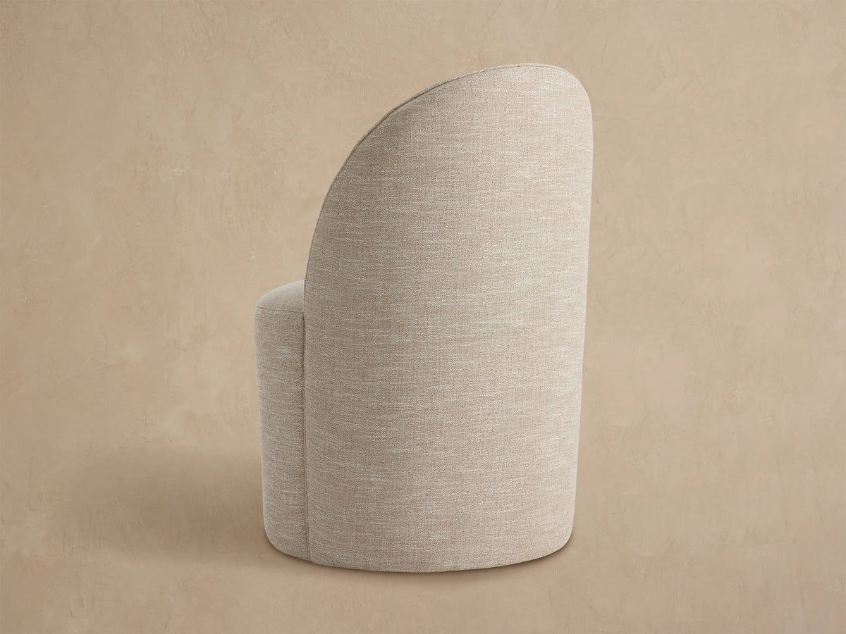 Kora Outdoor Dining Chair, close-up of curved back and seat upholstered in a textured light beige, off-white performance fabric.