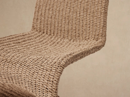 Leon Outdoor Dining Chair, front view. High-backed, armless chair crafted from textured light brown woven wicker, on a tiled floor.