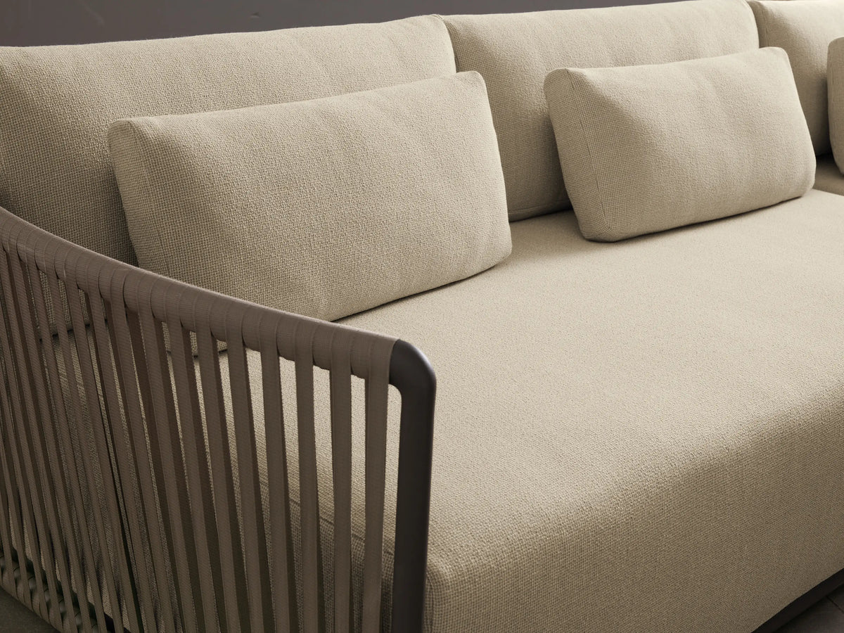 Lisbon Outdoor Two-Piece Sectional, L-shaped with light cream cushions, dark brown woven rope arms on a stone patio.