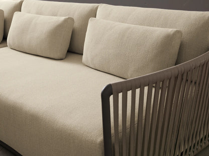 Lisbon Outdoor Two-Piece Sectional, L-shaped with light beige cushions & dark brown woven armrests on a paved patio.