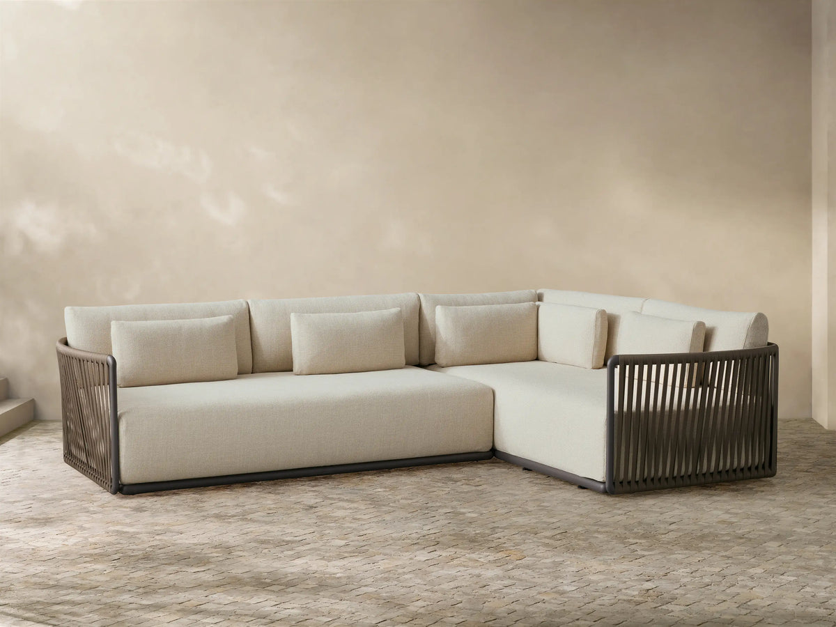 Natural Lisbon Outdoor Two-Piece Sectional with dark brown rope-wrapped frames and light beige cushions on a grey patio rug.