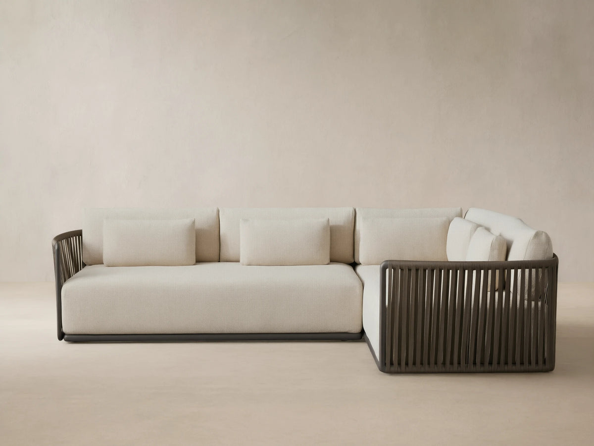Lisbon Outdoor Two-Piece Sectional, L-shaped, with light beige cushions and dark brown vertical woven rope frame on a patio.