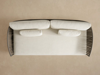 Lisbon Outdoor Sofa, back view. Dark brown woven rope frame with two light back cushions against a plain beige wall.