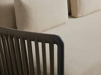 L-shaped Lisbon Outdoor Two-Piece Sectional with cream cushions & dark woven rope frame on light patterned stone flooring.